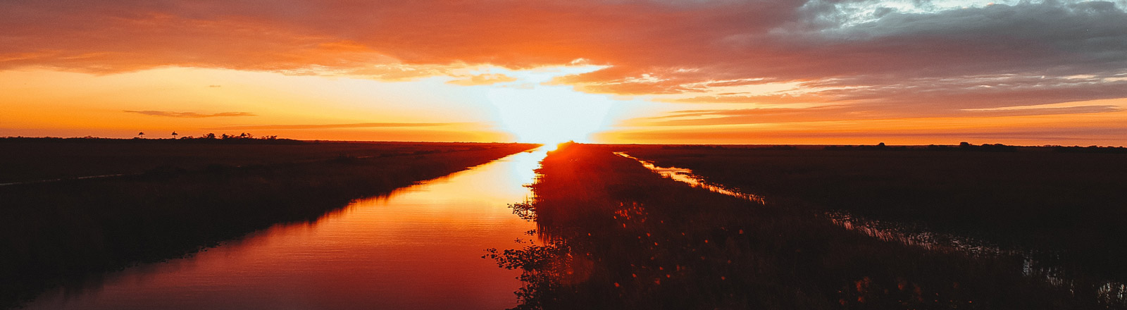 image of orange sunset overlooking wide shot of waterway in the everglades