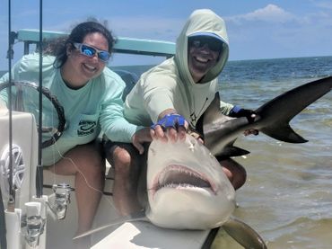 image of man and woman holding a caught shark