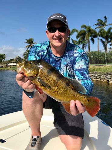 image of man holding a small fish up to camera